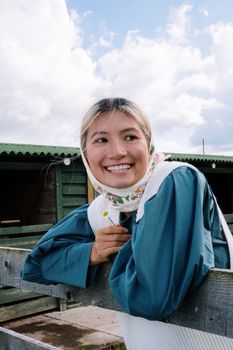 一位戴着头巾的女人微笑着靠在乡村户外的木栅栏上