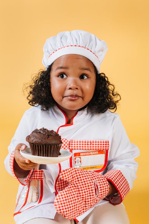 Mädchen Im Weißen Und Roten Langarmhemd, Das Schokoladen Cupcake Hält