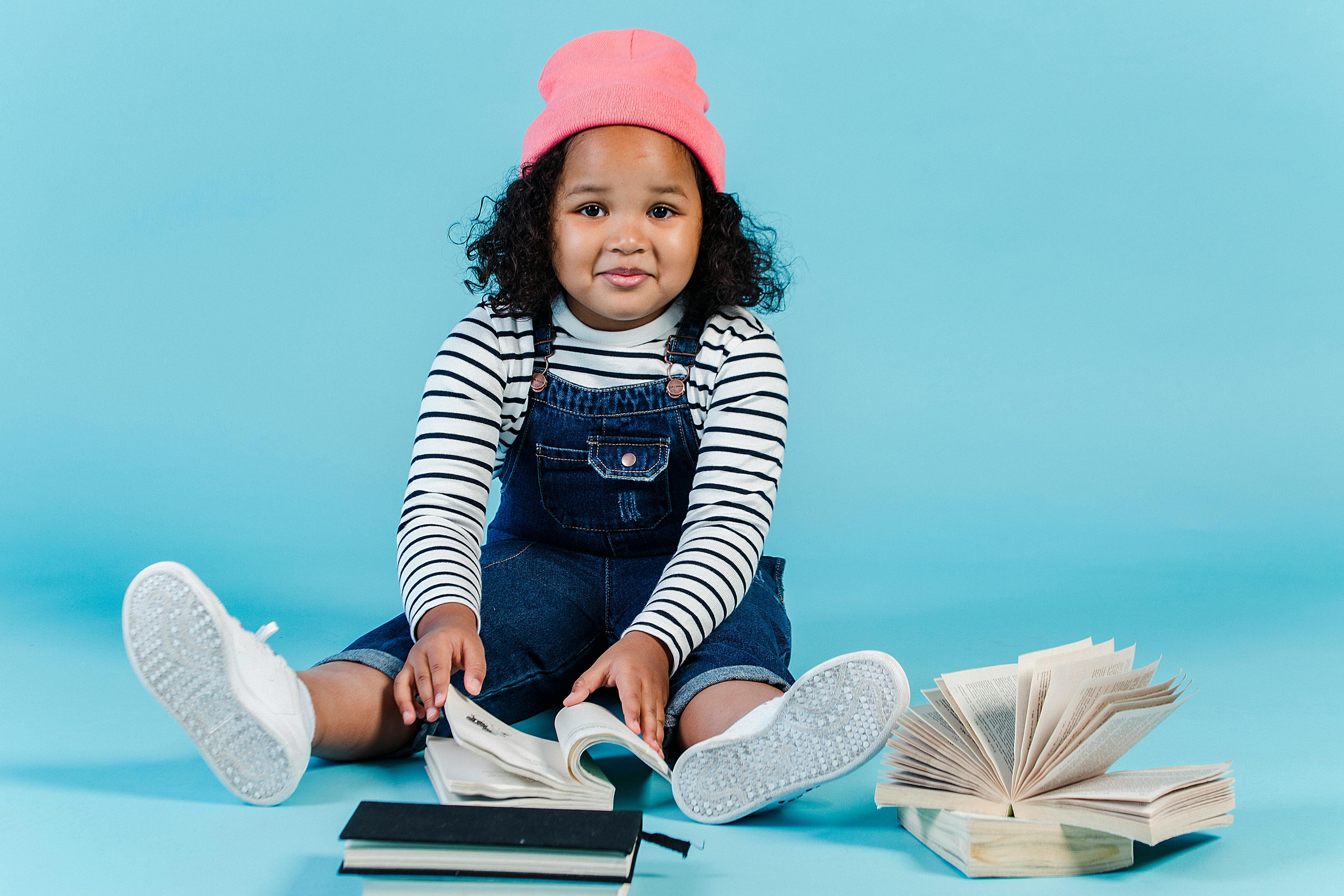 cheerful black girl sitting on floor with many books