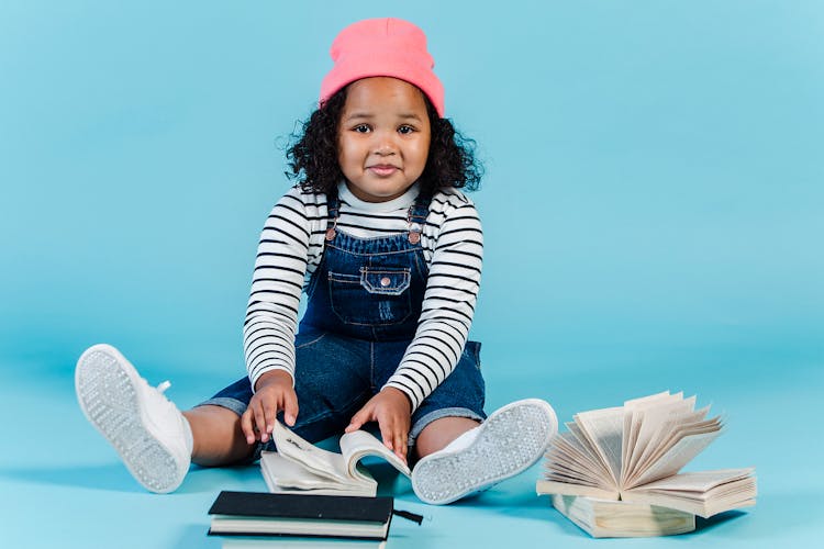 Cheerful Black Girl Sitting On Floor With Many Books