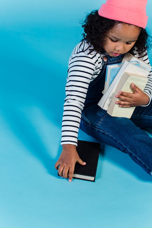 Black girl with books sitting on floor