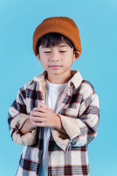 可爱的孩子穿着时尚的衣服，站在宁静的蓝色背景前