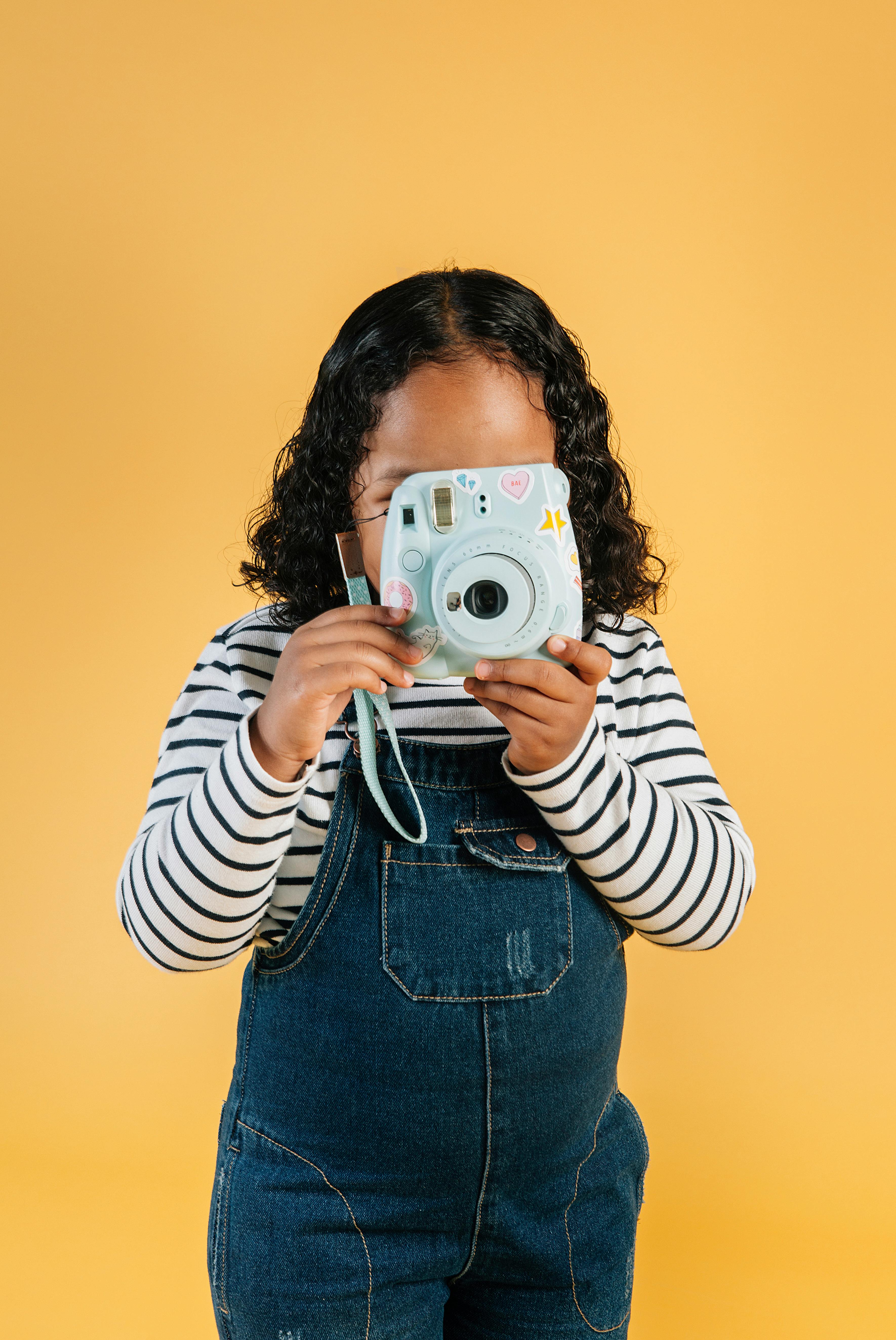 faceless ethnic girl taking picture on modern instant camera