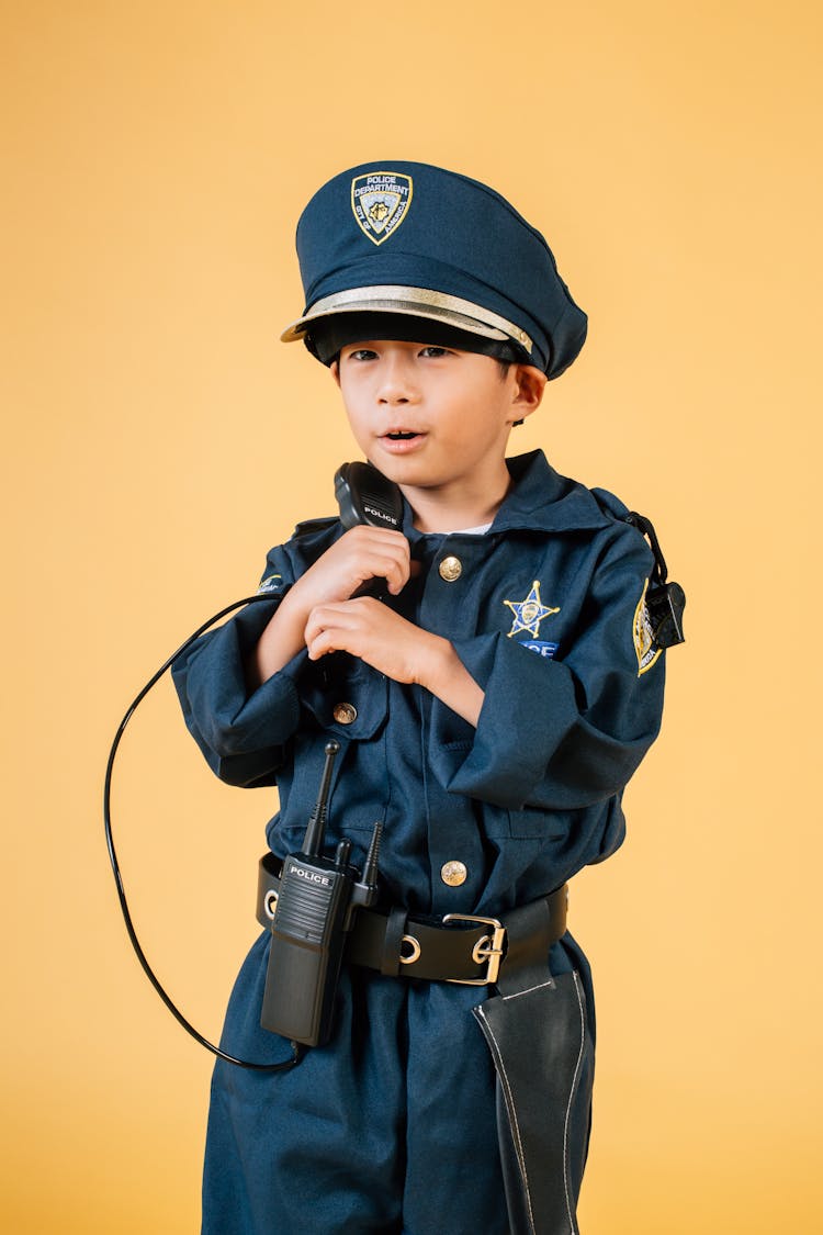 Funny Asian Boy Wearing Policeman Uniform In Studio