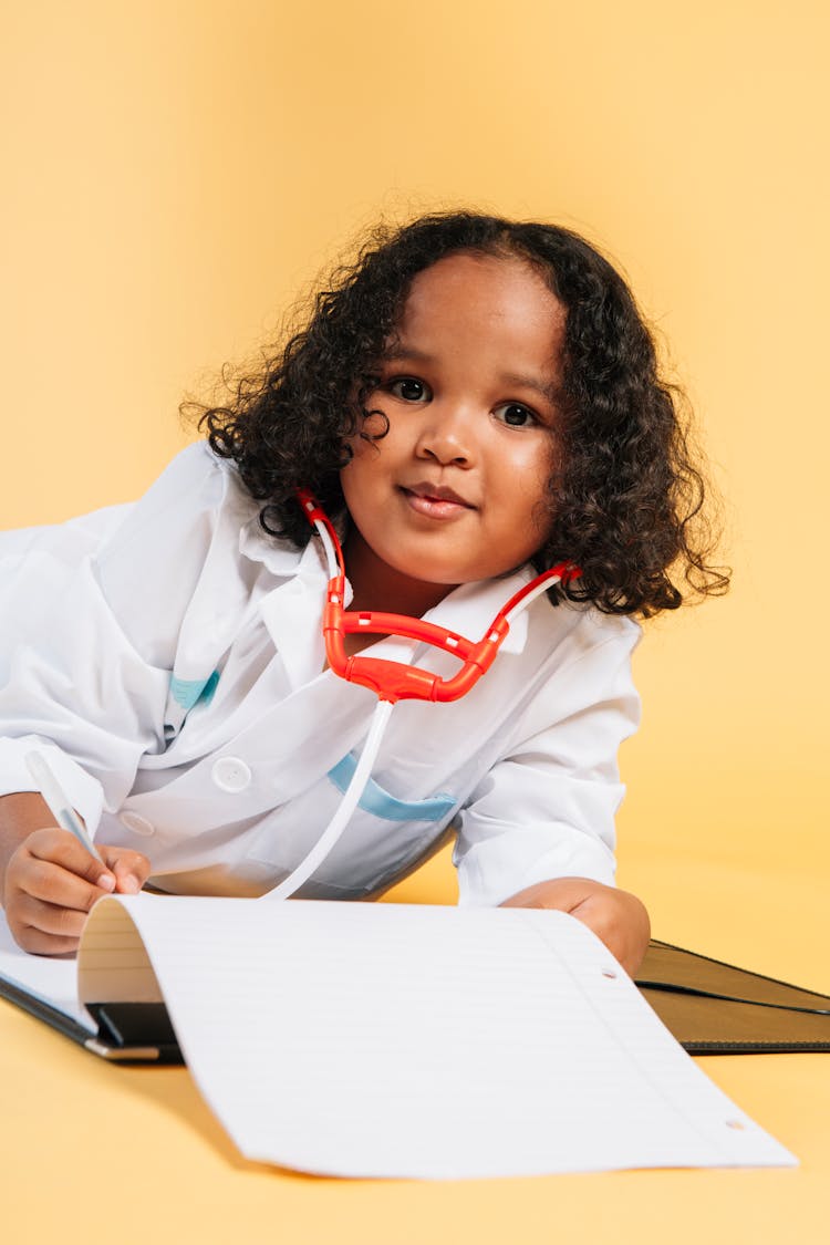 Cute Black Child Imitating Doctor While Playing In Studio