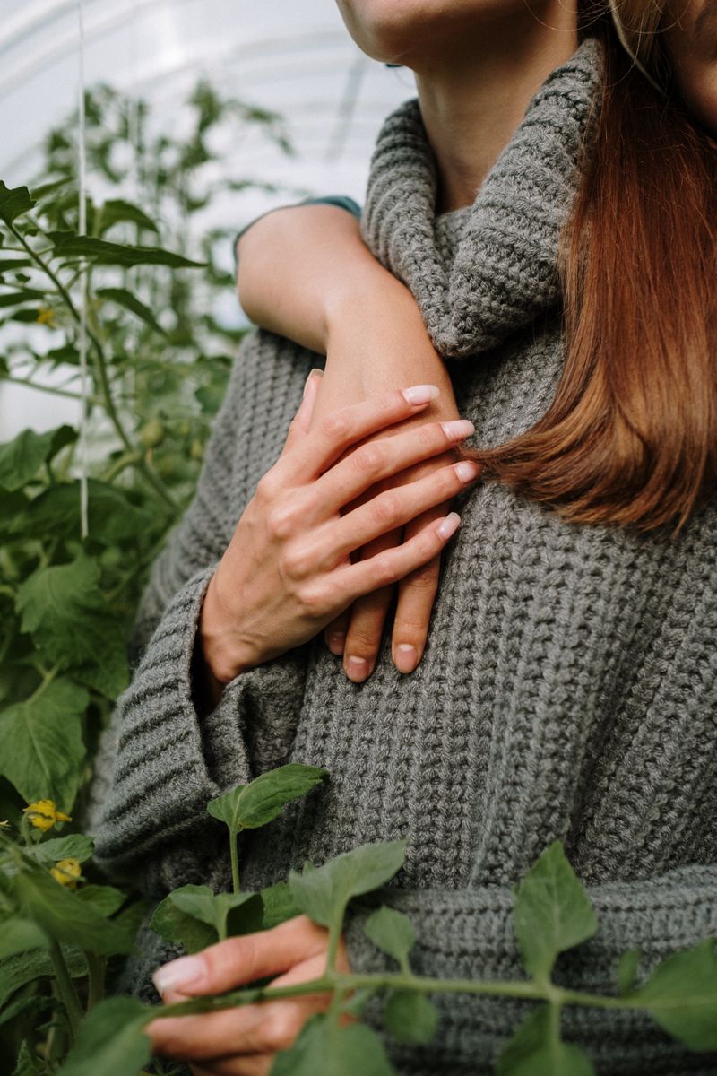A woman in a gray knit sweater holding green leaves representing personal growth and resilience after loss