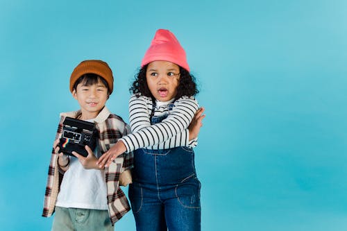 Little multiethnic friends with retro photo camera standing together