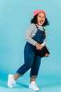 Joyful black girl with textbooks grimacing in studio