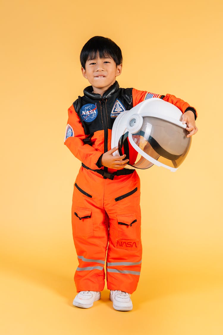 Cute Content Asian Boy In Spacesuit Holding Helmet