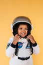 Smiling black girl wearing cosmonaut suit and touching helmet