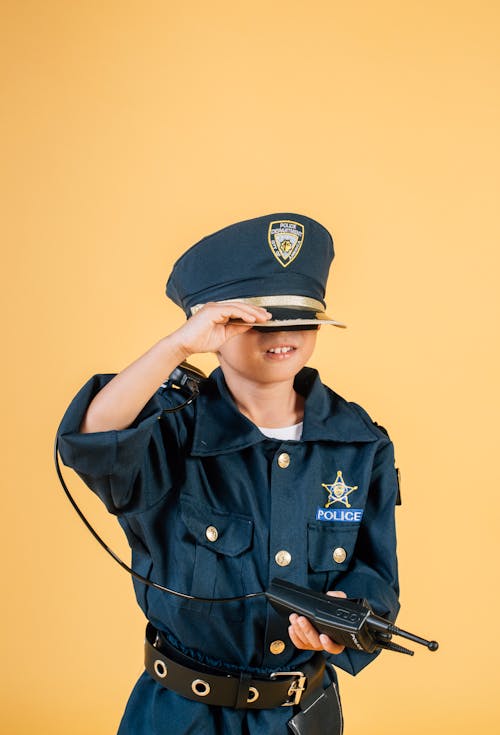 Cute boy in policeman costume touching cap