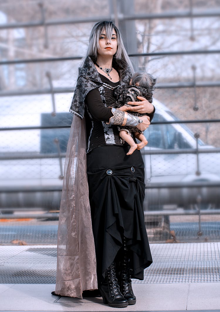 A Woman In Black Dress Holding A Baby