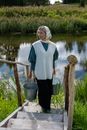 Woman in Blue Long Sleeve Shirt and Black Skirt Standing Beside Body of Water