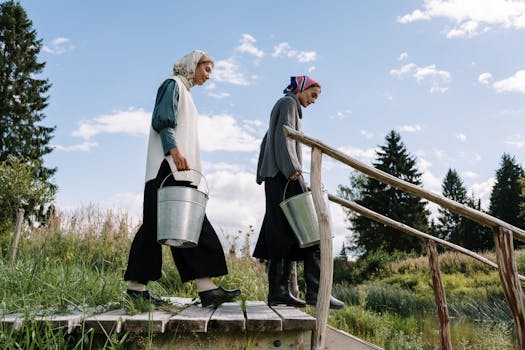 两个女人提着水桶，走过宁静乡村里的一座桥