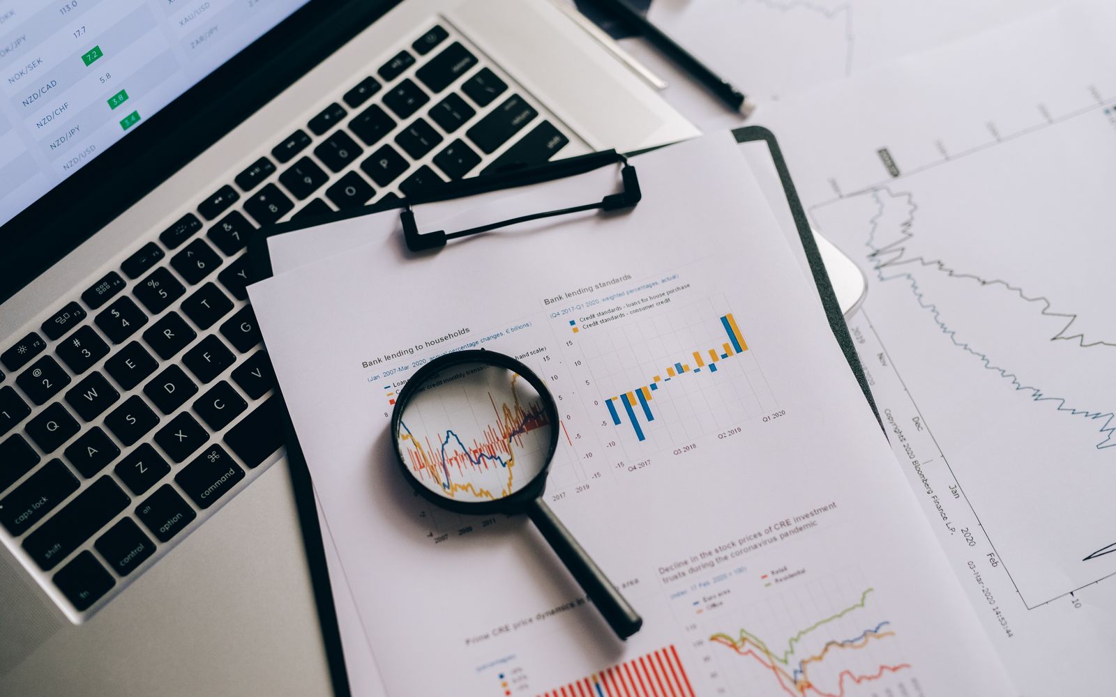 Loupe posée sur des graphiques statistiques à côté d’un ordinateur portable, photo Pexels