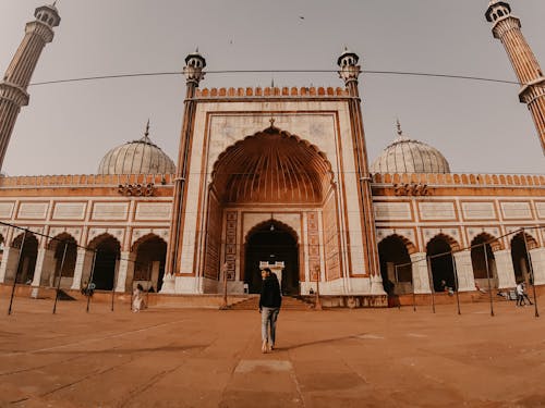 Man in Black Jacket Standing Near a Mosque