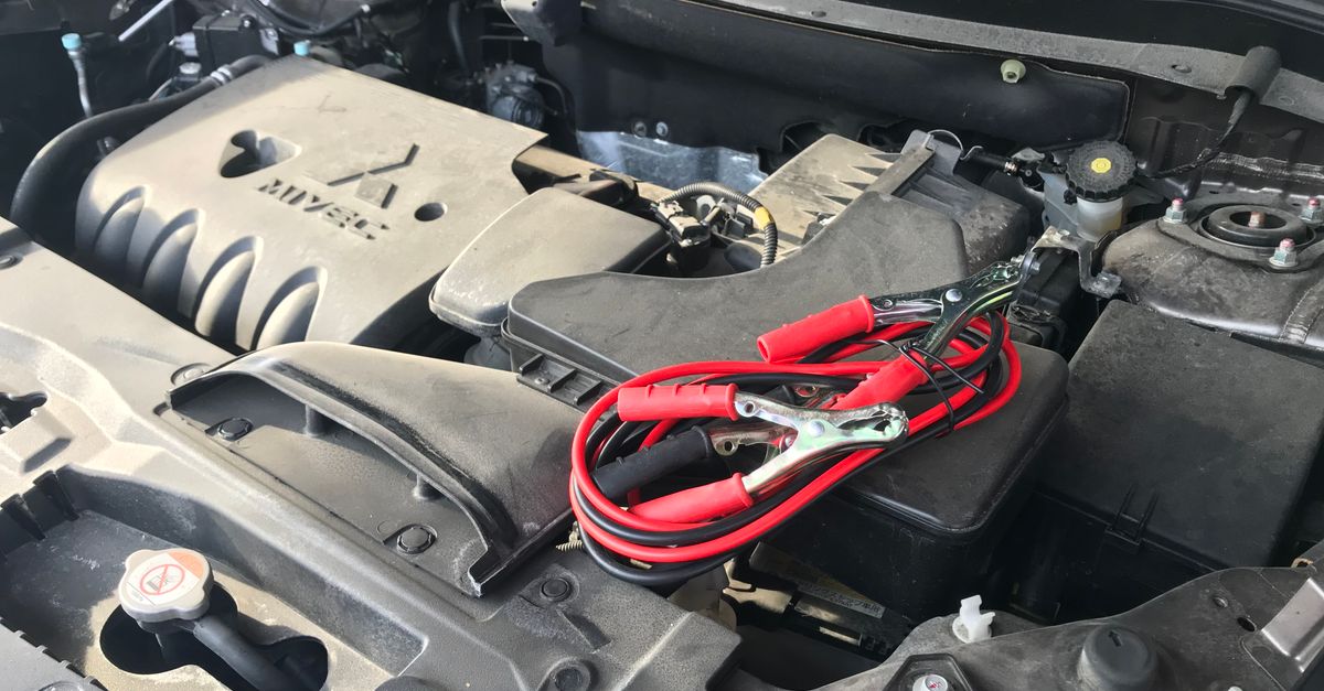 Detailed view of a car engine with red jumper cables, ideal for automotive themes.