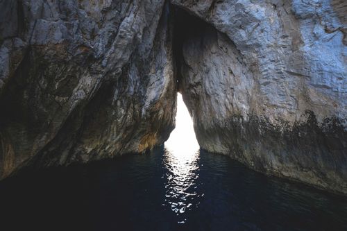 Free Spectacular scenery of stone formation with bright light from tunnel in rippling sea Stock Photo
