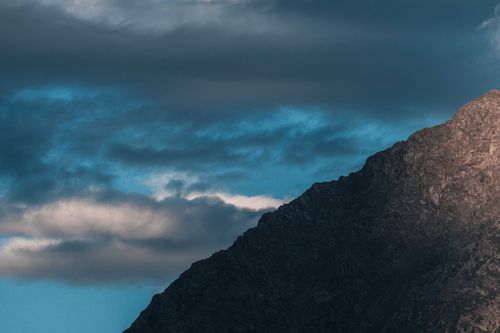Free Amazing view of rough mountain peak with rocky surface in shade under cloudy sky Stock Photo