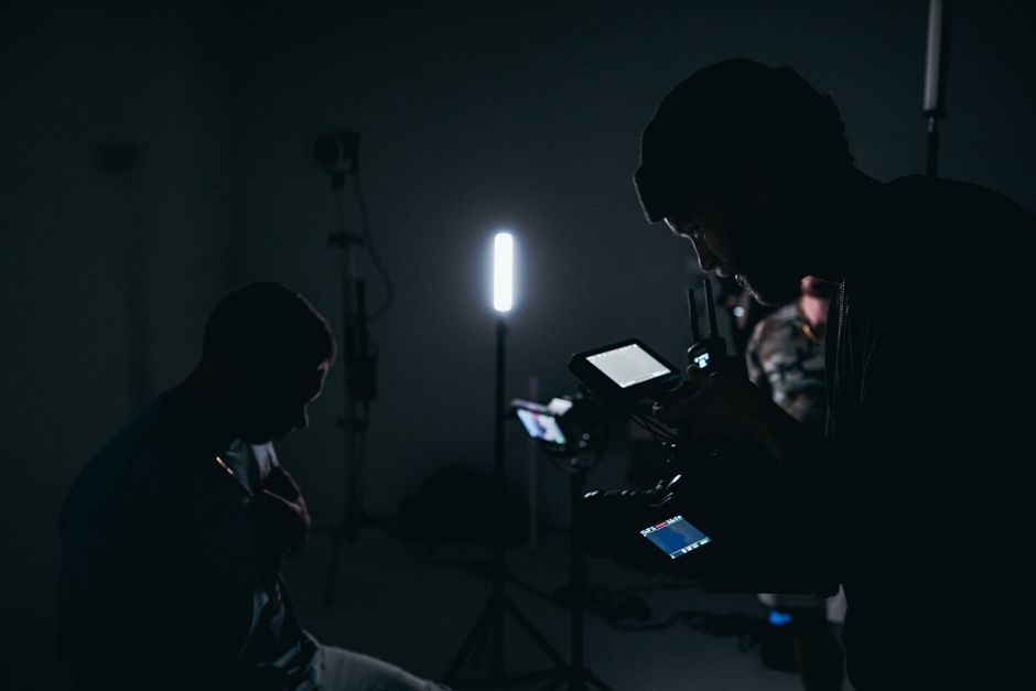 Cinematographer operating camera in dark studio with professional lighting