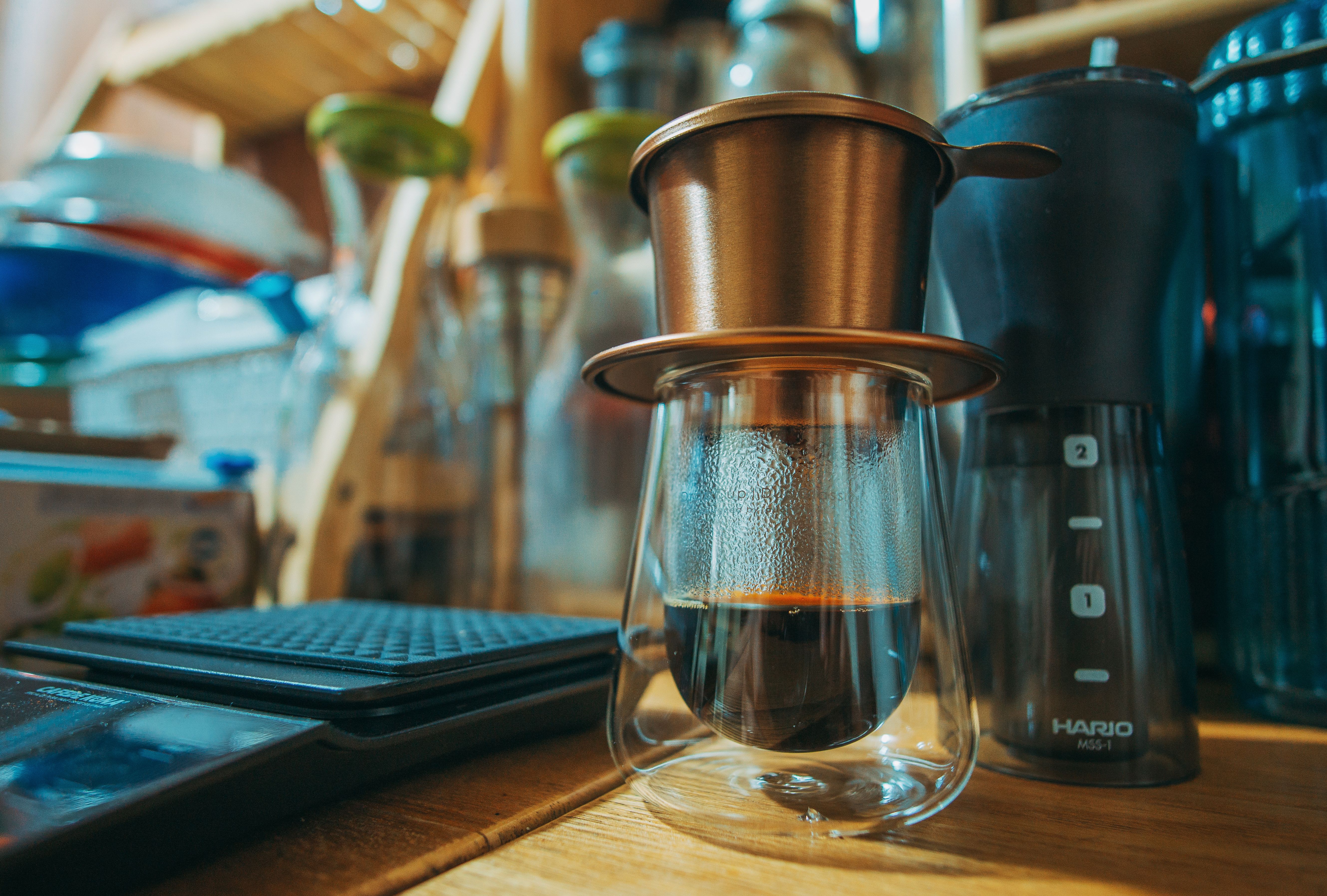 Close-up of a coffee brewing setup featuring a glass item and digital scale on a wooden counter.