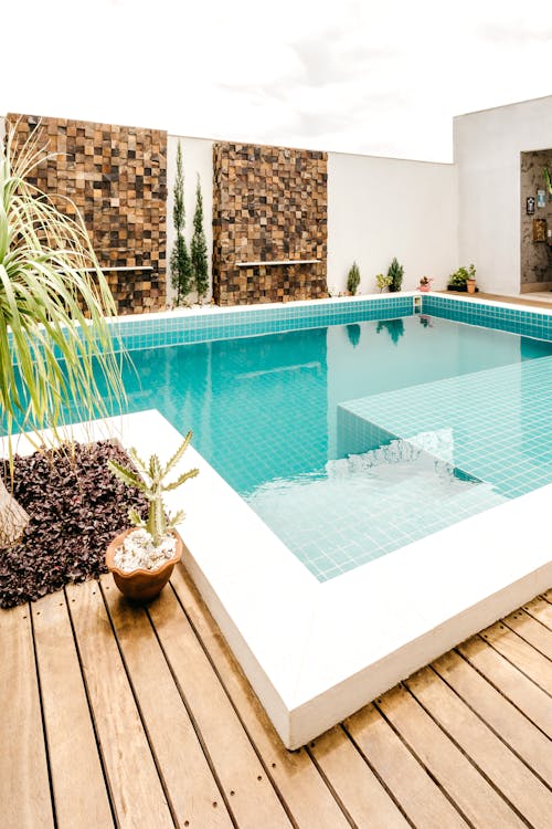 Comfortable lounge zone with swimming pool with clear water on terrace of modern villa in daytime
