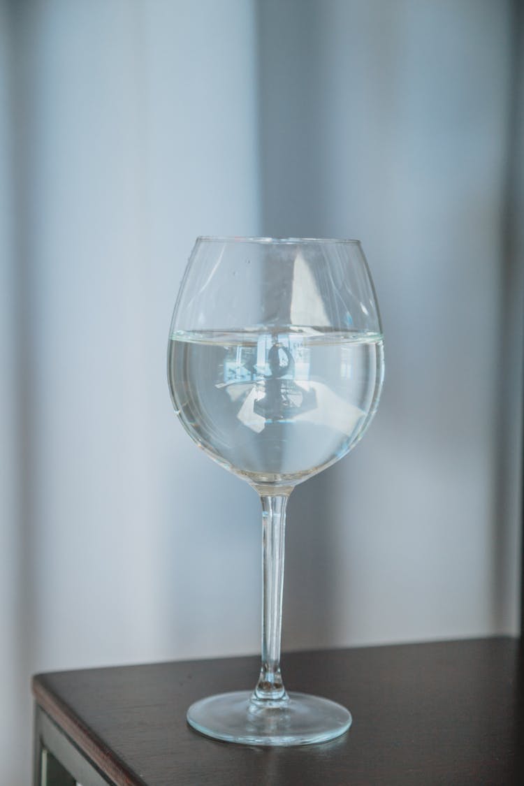 Glass Of Water With Ice Cube Placed On Table