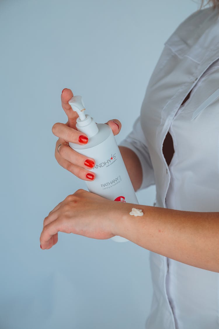 Faceless Female Cosmetologist Applying Lotion On Hand