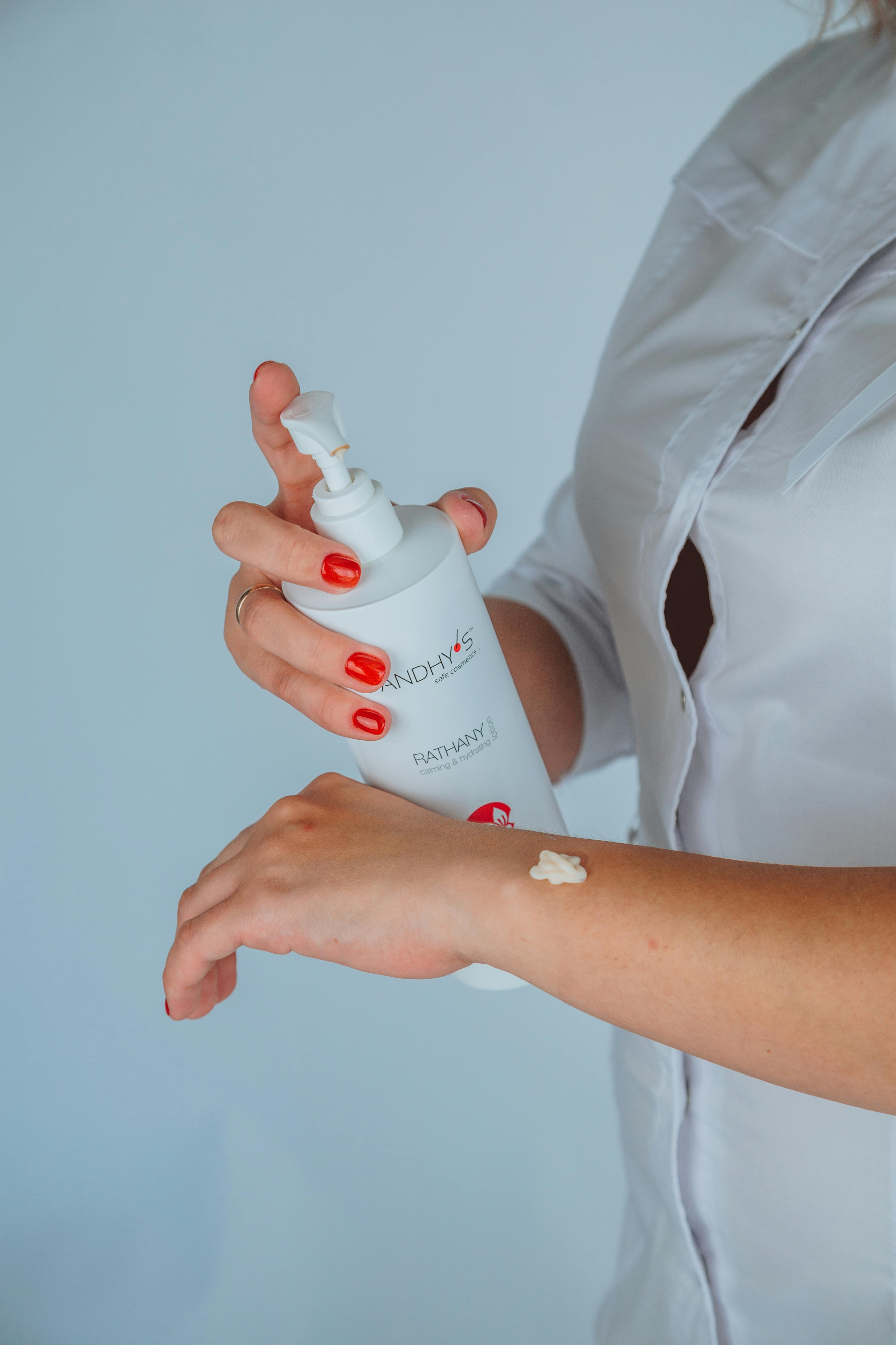 Faceless female cosmetologist applying lotion on hand \u00b7 Free Stock Photo