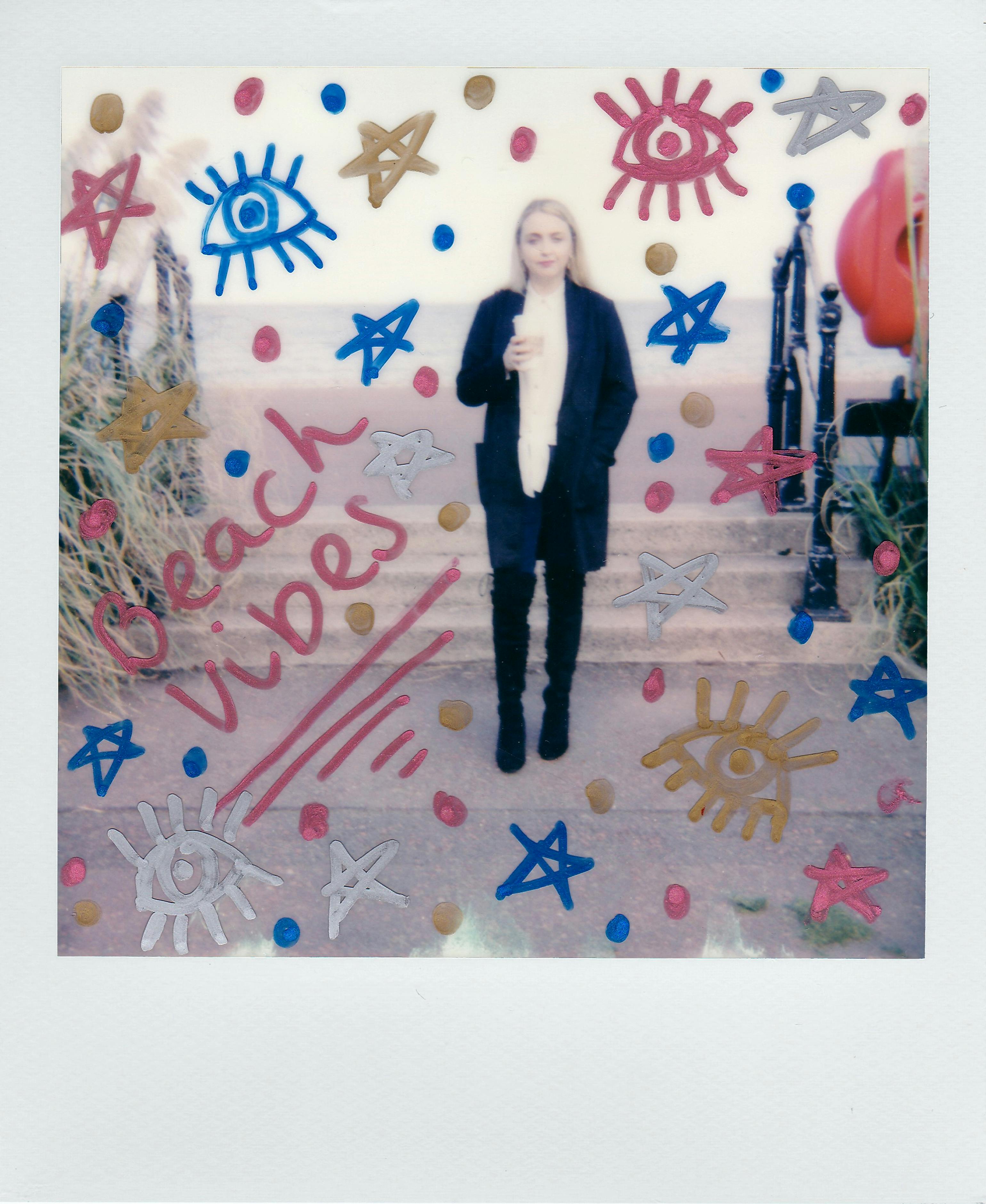 Polaroid photo of a woman at the beach with artistic doodles and text 'Beach vibes'.