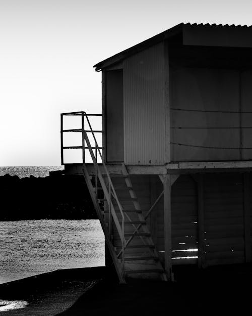 Grayscale Photo of a Boathouse with Stairs