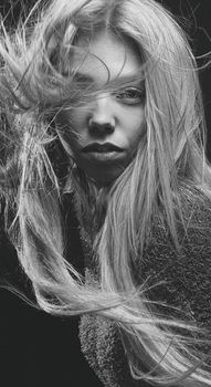 Striking black and white portrait of a woman with wind-swept hair showcasing intense beauty.