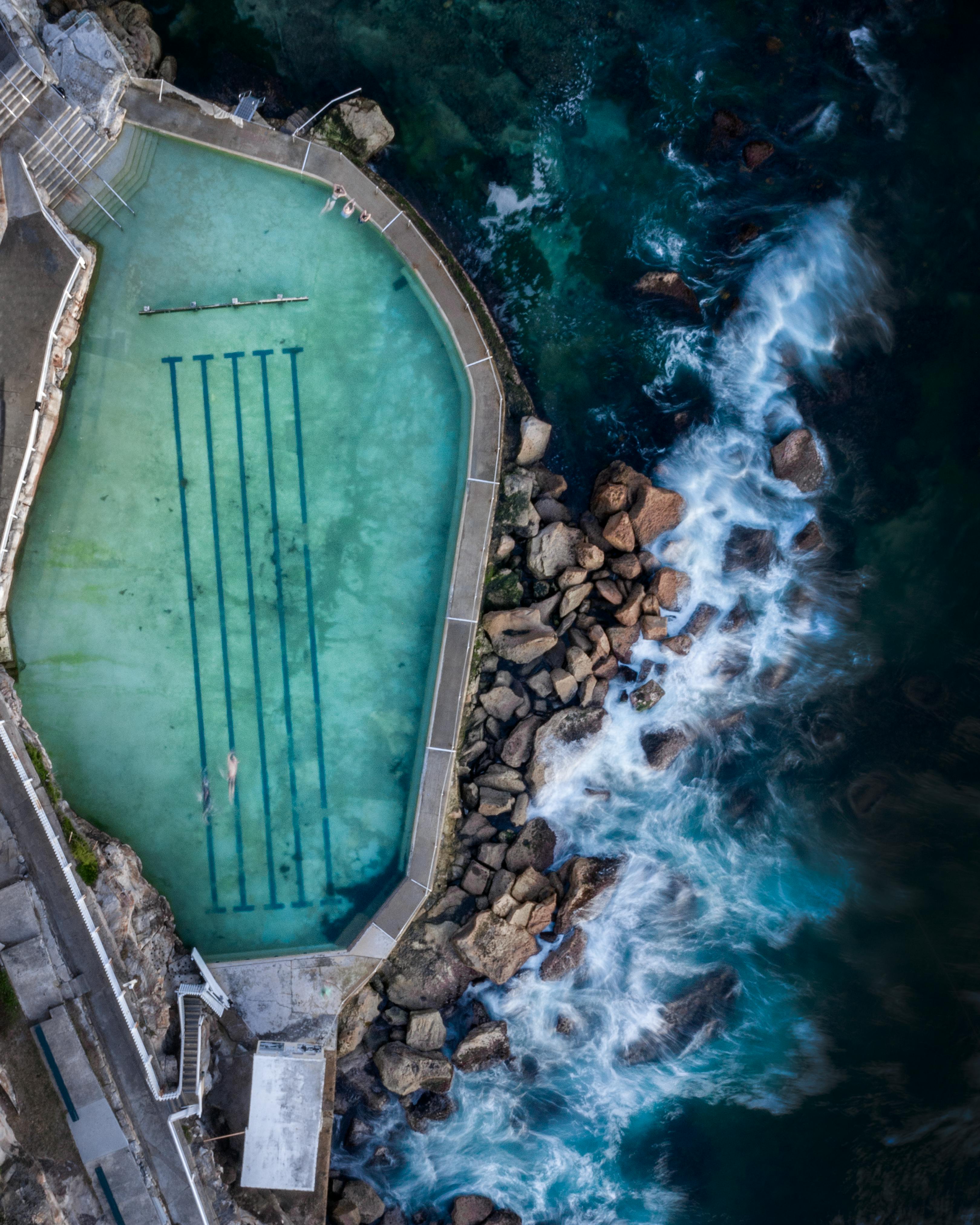 Stunning aerial shot of a seaside pool along Sydney's coastline, capturing waves crashing against rocks.