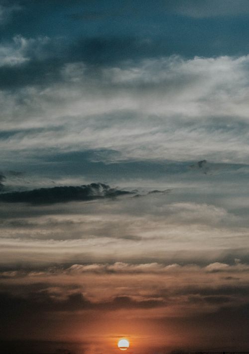 Free A mesmerizing view of the sun setting or rising with dramatic cloud formations above. Stock Photo