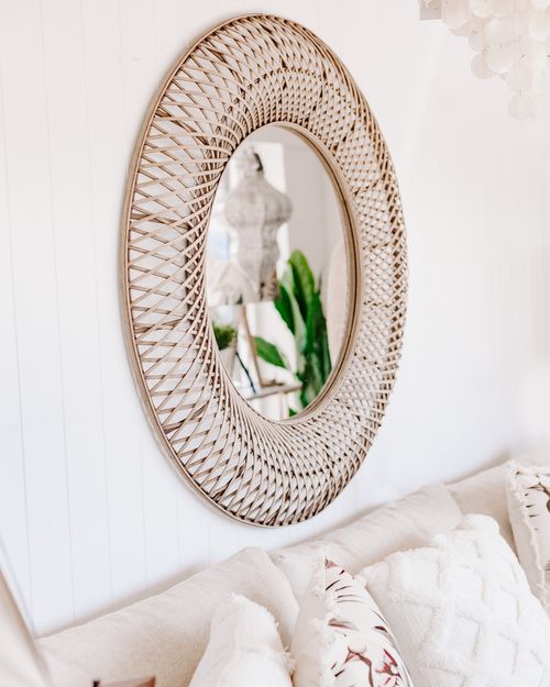 Free Stylish oval shaped mirror with wired frame placed on white wall above cozy soft couch in light living room Stock Photo