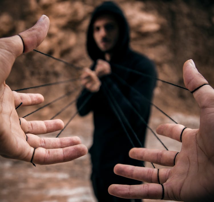 Man Pulling Strings Attached To Another Persons Fingers 