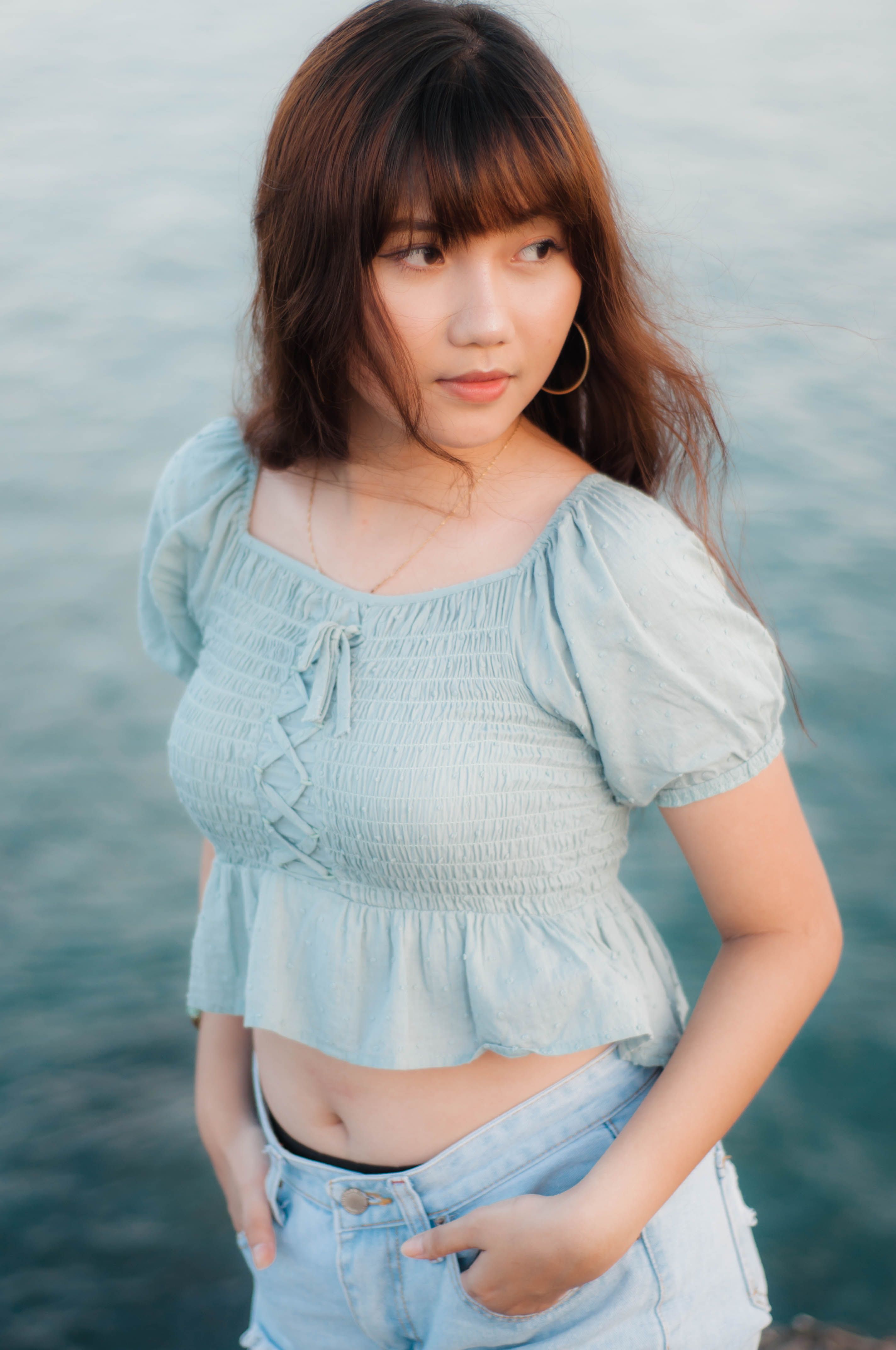 湖边，一位穿着牛仔布的年轻女子正悠闲地坐着