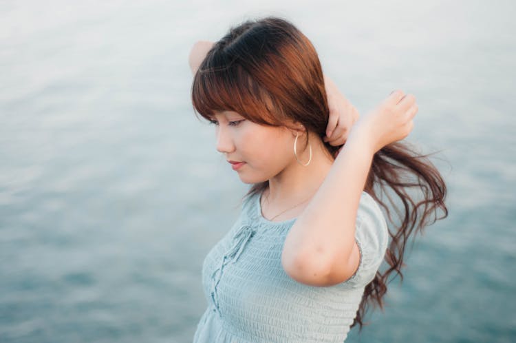 Young Woman Touching Hair On Sea Background