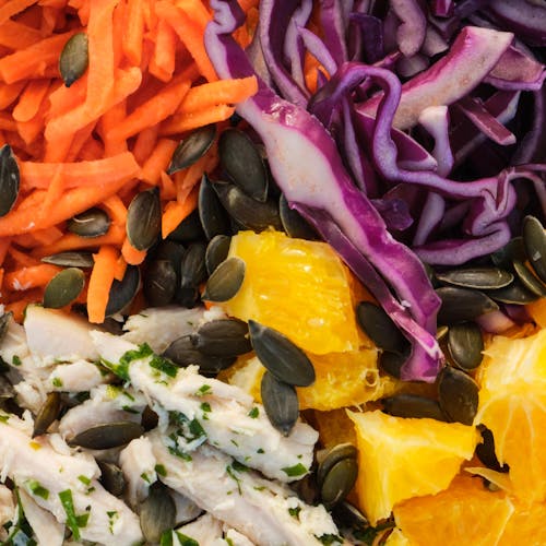 Closeup of appetizing fresh healthy vegetables and fruits in salad mix with pumpkin seeds