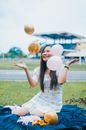 Cheerful Asian woman with balloons on lawn