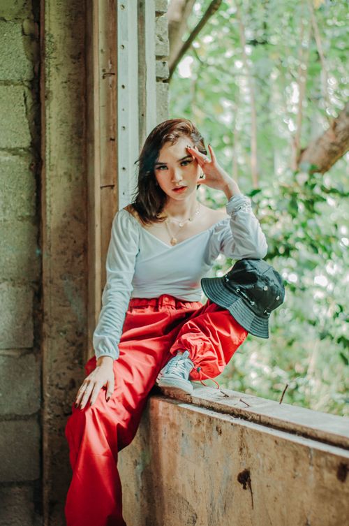Free Confident young female millennial wearing stylish clothes touching forehead in shabby destructed building and looking at camera Stock Photo