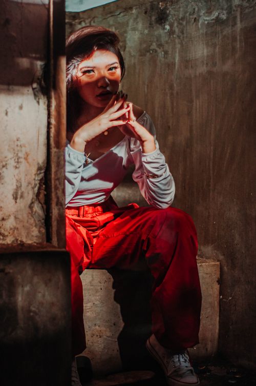 Free Asian female with connected fingers looking at camera while sitting in shabby building Stock Photo