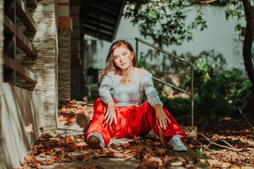 Free Full body of serious ethnic female sitting on wooden stairs with spreading legs and looking at camera in autumn Stock Photo