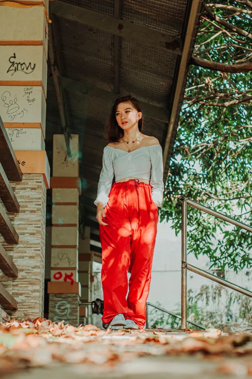 Free Ground level of ethnic female teenager in trendy wear with hand in pocket looking away against building Stock Photo