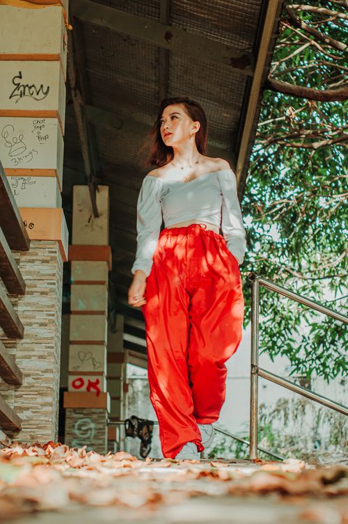Free Ground level of ethnic female adolescent in stylish clothes with hand in pocket looking away while strolling against house Stock Photo