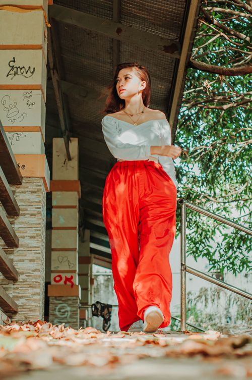 Free Ground level of trendy ethnic female adolescent looking away while strolling on walkway against building in autumn Stock Photo
