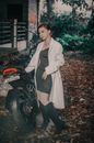 Fashionable woman near motorcycle in countryside