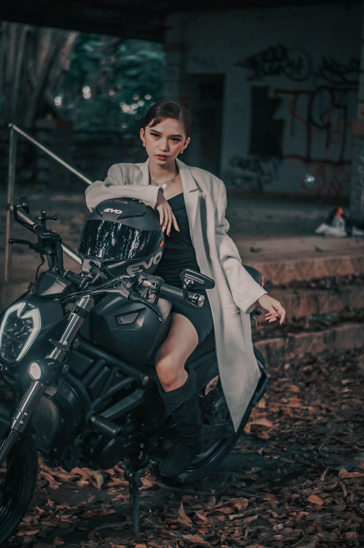 Confident Woman On Motorcycle Near Old House