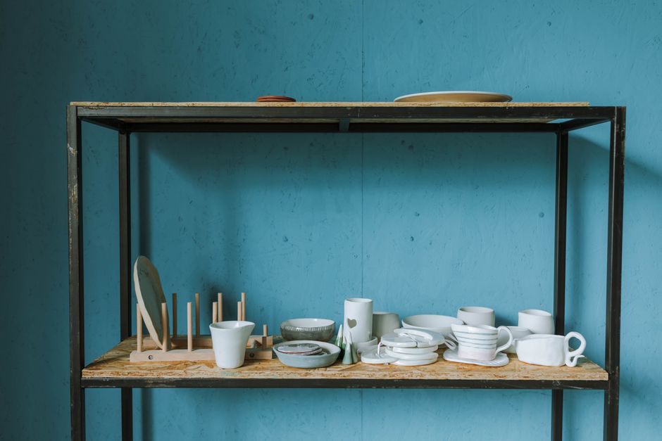 Minimalist setup with white ceramic dishes on a rustic shelf against a blue background.