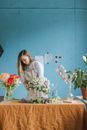 Woman Pruning Flowers on Clear Glass Vases